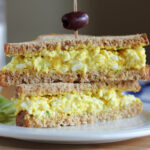 Two egg salad sandwich halves stacked on top of each other.