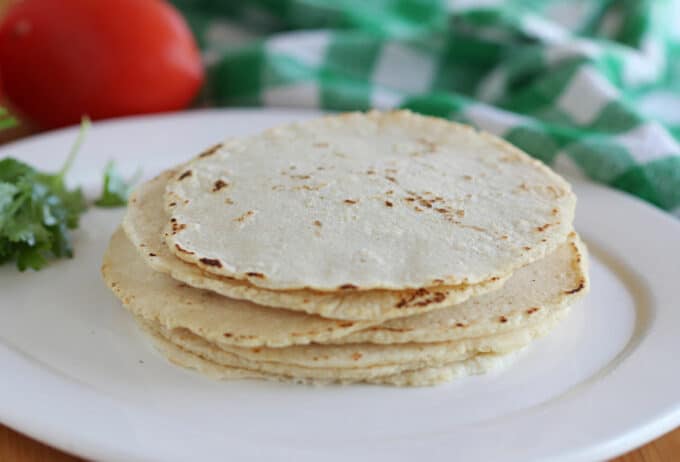Stack of corn tortillas on a white plate.