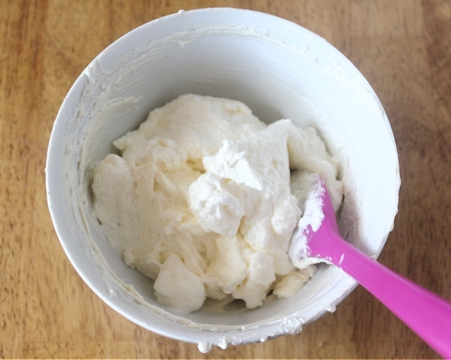 Yogurt frosting in a bowl with a purple spatula.
