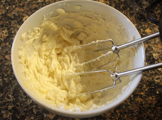 Whipping yogurt and butter in a white bowl.