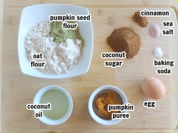 Ingredients laid out on a wood cutting board, including oat flour and pumpkin puree.