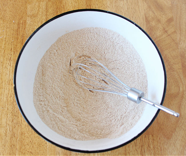 Flour in a white bowl with a whisk.