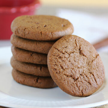 Stack of five ginger snap cookies on a white plate.