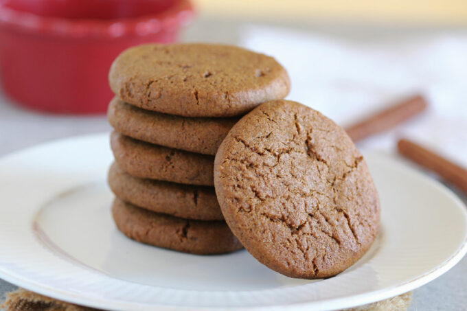 Stack of five ginger snap cookies on a white plate.