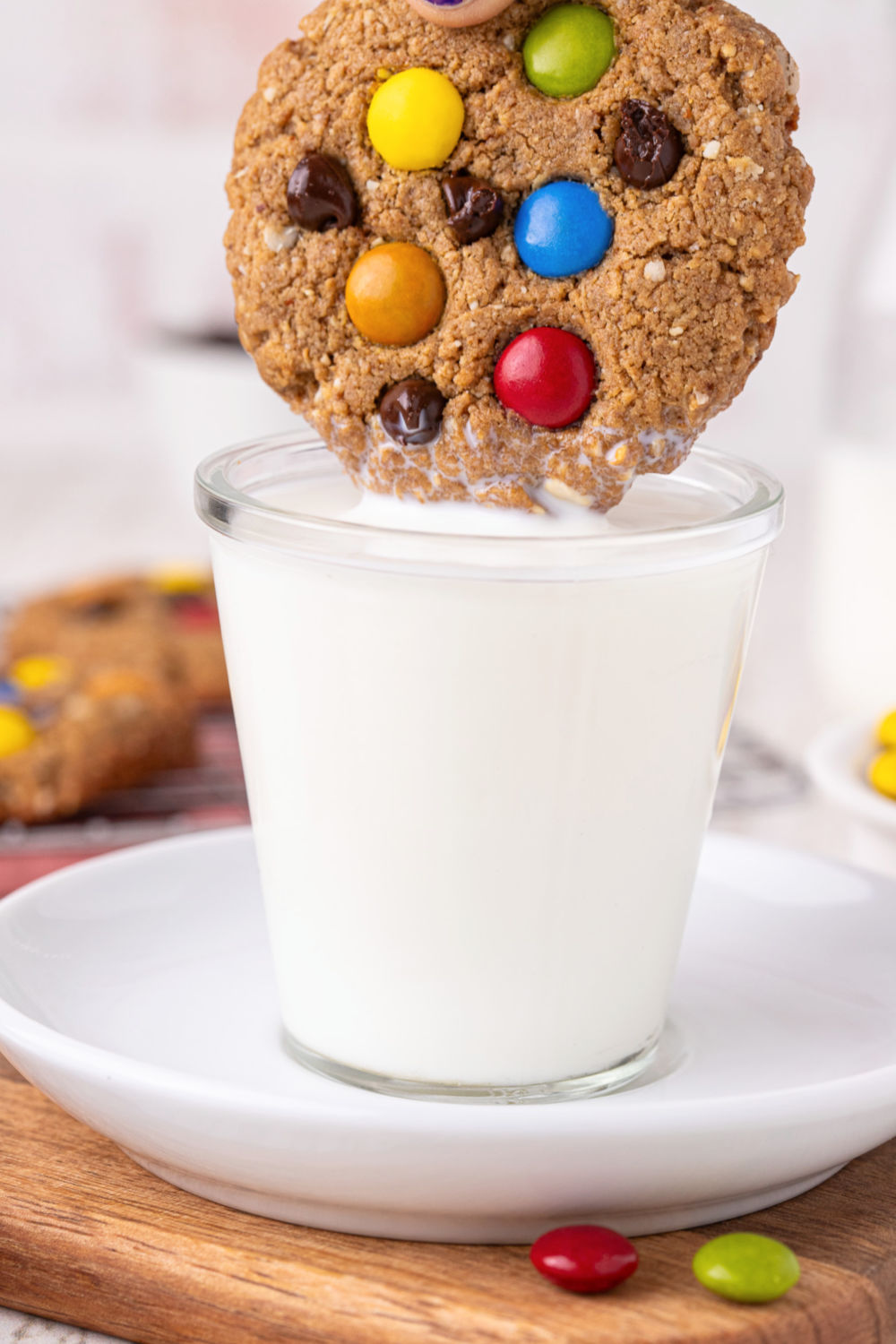 Dipping a cookie with M&Ms in a glass of milk.