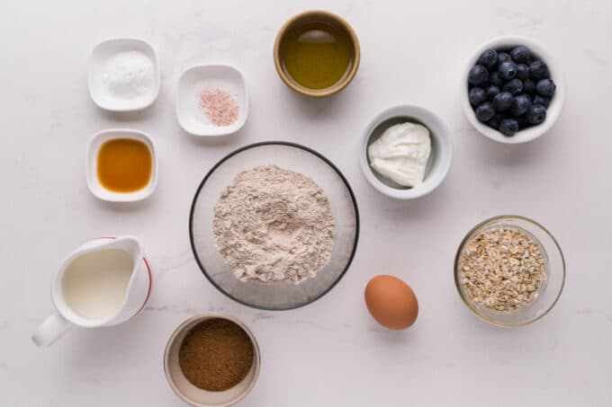 Flour, oats, blueberries, and other ingredients for muffins laid out on a table.