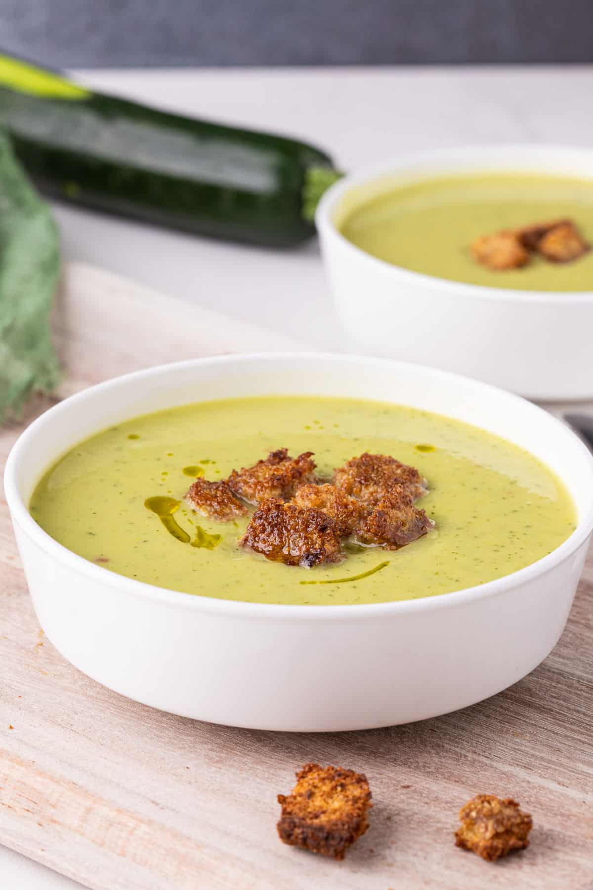 Zucchini soup in a bowl topped with croutons.