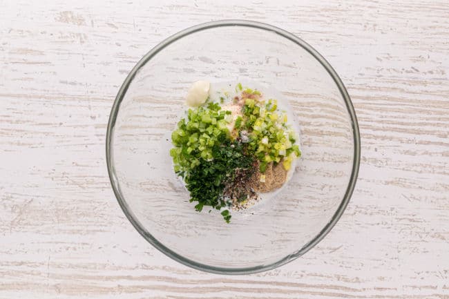 Herbs and vegetables in a glass bowl.