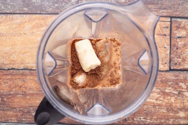 Milk, yogurt, cocoa, and banana in a blender.