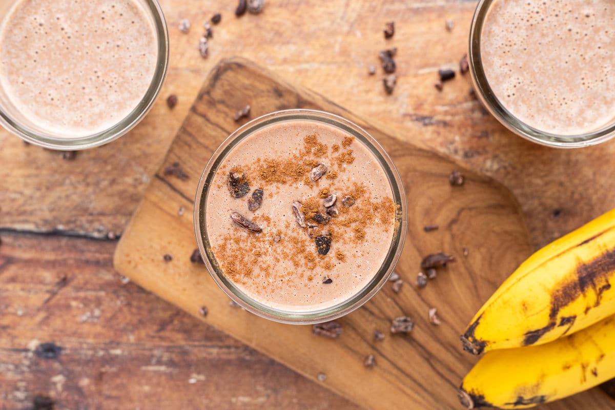 Chocolate smoothie in a glass topped with cinnamon and cacao nibs.