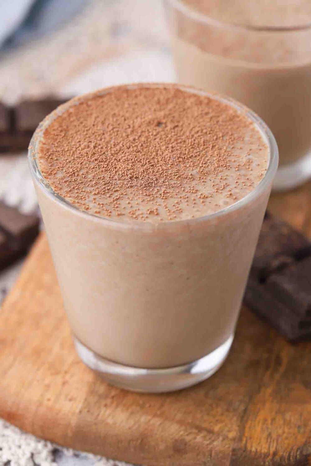 Glass of chocolate milk topped with cocoa powder.